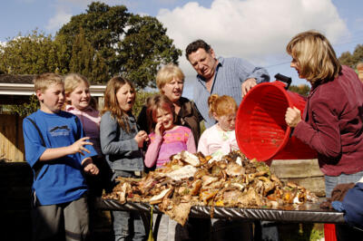 q) WA$TED! (Crump family with table of rubbish mid-shot)